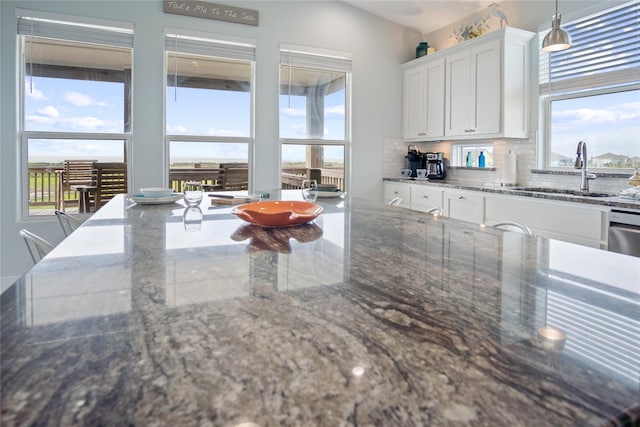 kitchen featuring a sink, tasteful backsplash, plenty of natural light, and white cabinets