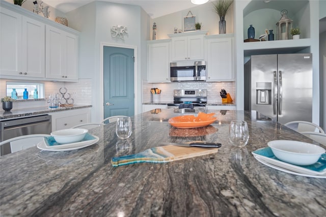 4413 Strand Ave, Port Bolivar, TX 77650 - kitchen with stainless steel appliances, white cabinets, decorative backsplash, and dark stone countertops