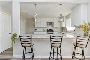 kitchen featuring appliances with stainless steel finishes, light countertops, white cabinetry, a peninsula, and wood finished floors