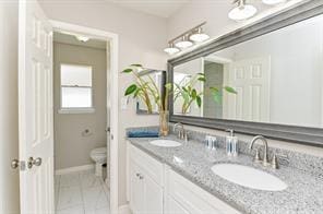 full bathroom with a sink, double vanity, toilet, marble finish floor, and baseboards