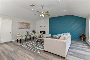 living area featuring visible vents, a fireplace, a ceiling fan, wood finished floors, and vaulted ceiling