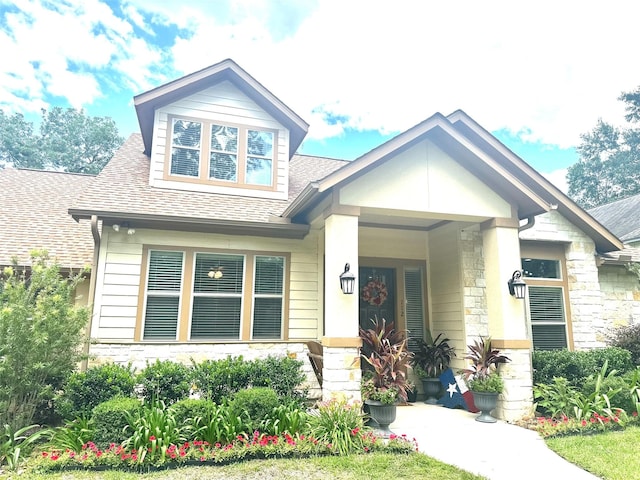 112 Timberside Dr, Conroe, TX 77304 - craftsman house with stone siding, a shingled roof, and a porch