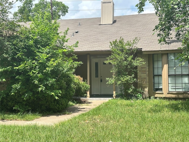view of exterior entry featuring a chimney and roof with shingles