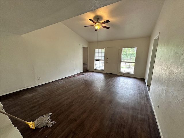 unfurnished living room featuring a textured wall, baseboards, dark wood-style floors, a ceiling fan, and vaulted ceiling
