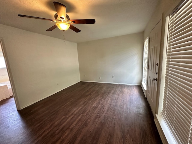 unfurnished room featuring ceiling fan, dark wood-style floors, and baseboards