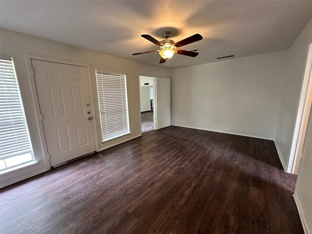 foyer with dark wood-type flooring, a ceiling fan, and visible vents