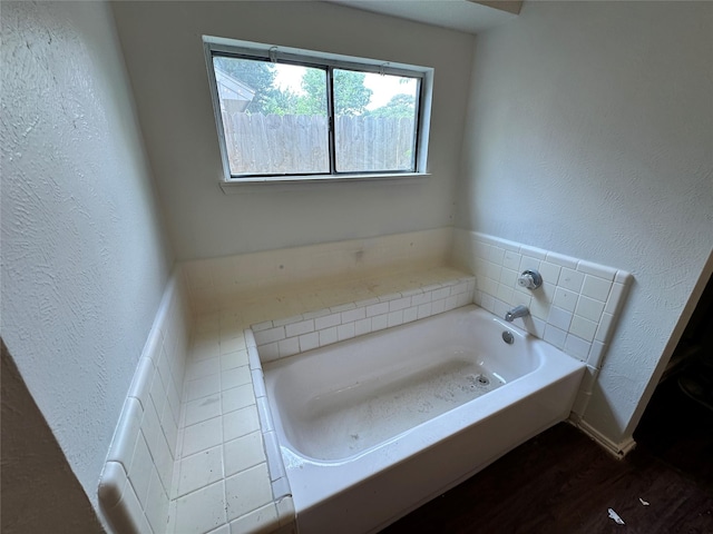 bathroom featuring a textured wall, a garden tub, and wood finished floors