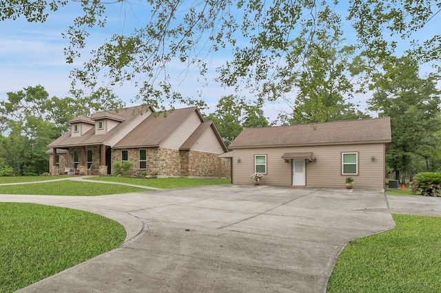 9948 Roda Dr, Conroe, TX 77303 - view of front facade with concrete driveway, covered porch, stone siding, and a front lawn