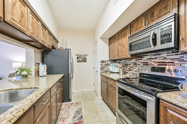kitchen with light stone counters, stainless steel appliances, baseboards, light tile patterned floors, and backsplash