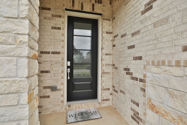 view of exterior entry featuring brick siding