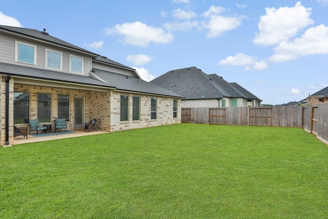 back of property with a fenced backyard, a patio, and a lawn