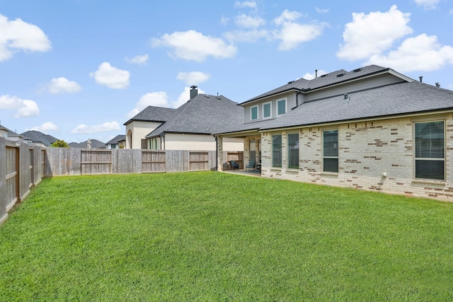 back of house featuring a yard, a shingled roof, and a fenced backyard