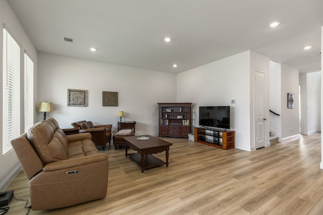 living area featuring stairs, a healthy amount of sunlight, and light wood finished floors