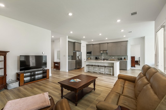 living room featuring light wood-style floors, recessed lighting, and visible vents