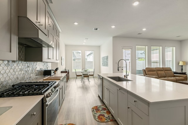 kitchen with visible vents, light wood-type flooring, gray cabinets, a sink, and stainless steel appliances