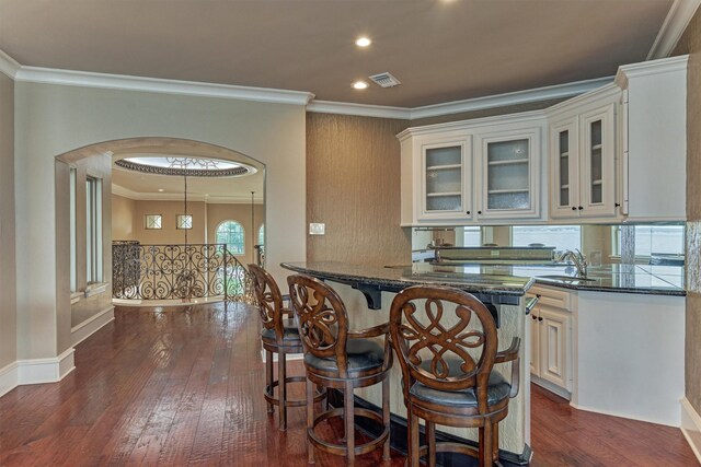 28822 Saddle Oak Dr, Montgomery, TX 77356 - kitchen with a kitchen bar, visible vents, dark wood-style floors, glass insert cabinets, and ornamental molding