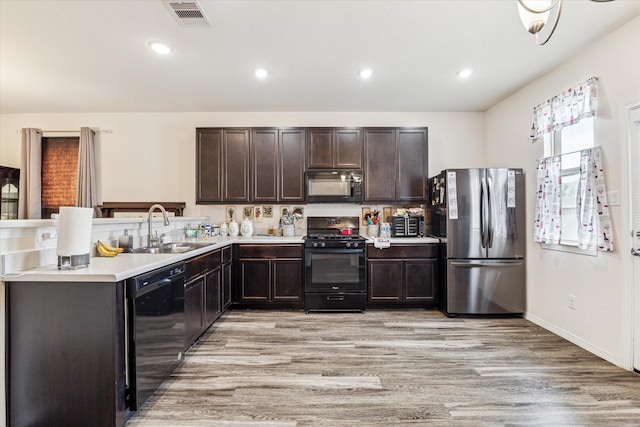 13127 Clifton Hill Ln, Houston, TX 77044 - kitchen with visible vents, dark brown cabinets, light wood-style floors, a sink, and black appliances