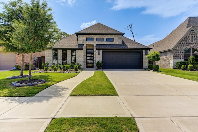 prairie-style home featuring a shingled roof, a garage, brick siding, and a front yard