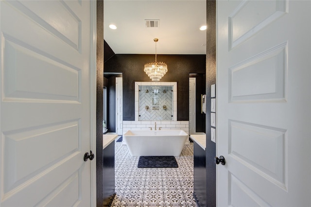 full bathroom with a soaking tub, tile patterned flooring, visible vents, and an inviting chandelier
