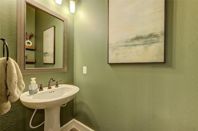 bathroom with a textured wall and baseboards