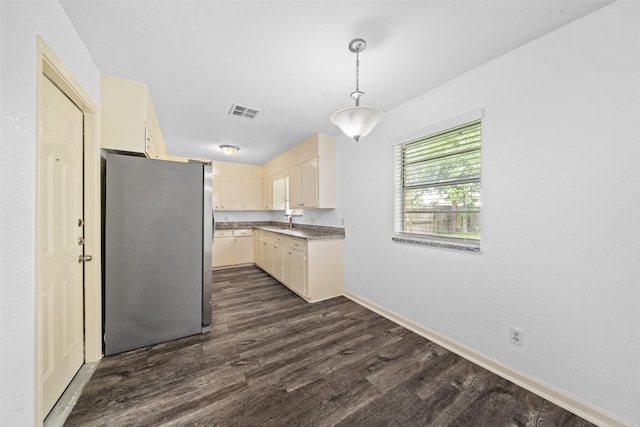 kitchen with dark wood-style flooring, decorative light fixtures, visible vents, baseboards, and freestanding refrigerator