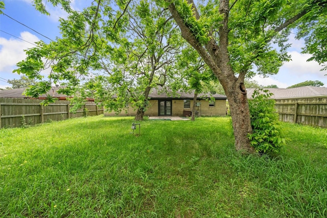 view of yard featuring fence and french doors