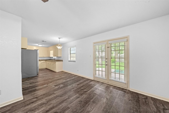 unfurnished living room with dark wood-type flooring and baseboards
