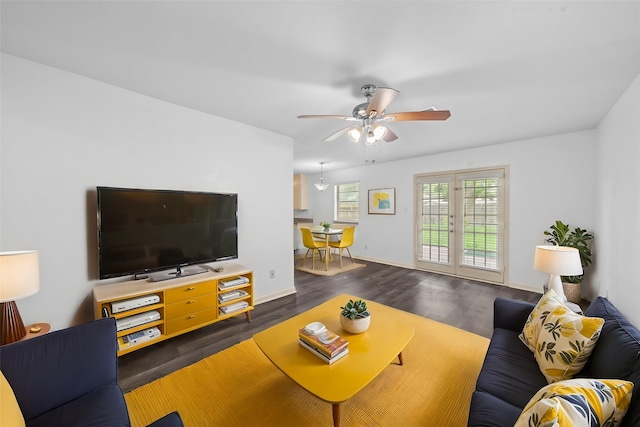 living area featuring baseboards, a ceiling fan, and dark wood-style floors