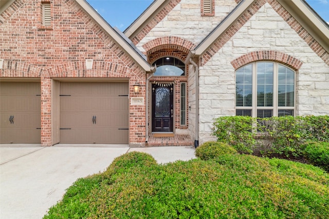 11143 Dunstan Hill Dr, Richmond, TX 77407 - view of exterior entry featuring concrete driveway, an attached garage, stone siding, and brick siding