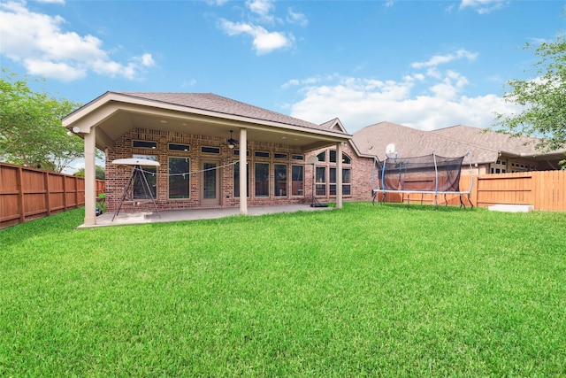 11143 Dunstan Hill Dr, Richmond, TX 77407 - back of house featuring a trampoline, brick siding, and a patio