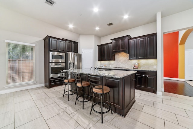 11143 Dunstan Hill Dr, Richmond, TX 77407 - kitchen with appliances with stainless steel finishes, a kitchen breakfast bar, arched walkways, light stone countertops, and tasteful backsplash