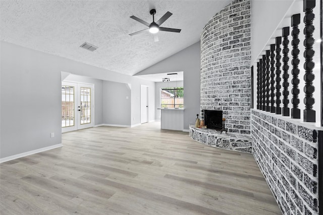 unfurnished living room featuring a brick fireplace, a textured ceiling, a ceiling fan, baseboards, and visible vents
