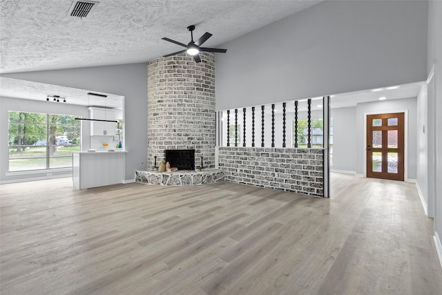 unfurnished living room featuring a textured ceiling, high vaulted ceiling, visible vents, and ceiling fan
