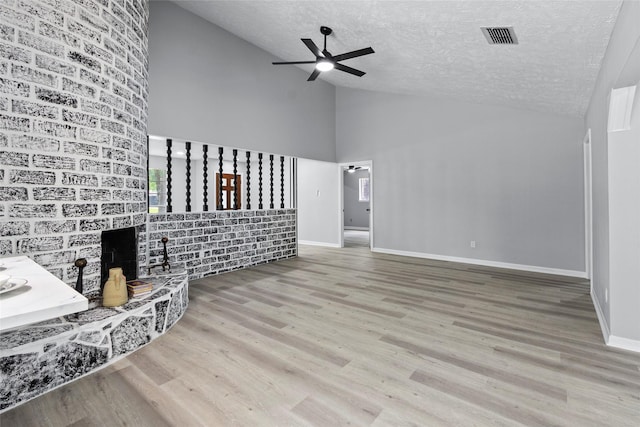 unfurnished living room with visible vents, wood finished floors, high vaulted ceiling, a textured ceiling, and a ceiling fan