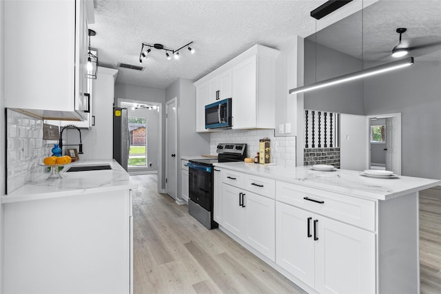 kitchen with visible vents, appliances with stainless steel finishes, a sink, a peninsula, and light wood-style floors