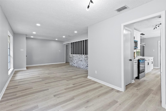 unfurnished living room featuring recessed lighting, light wood-style flooring, a textured ceiling, and visible vents