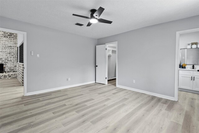 unfurnished bedroom with light wood-style floors, a textured ceiling, and a spacious closet