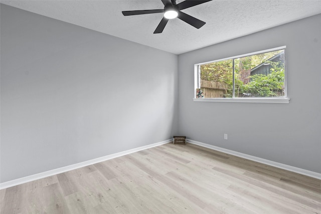 unfurnished room with ceiling fan, a textured ceiling, baseboards, and wood finished floors