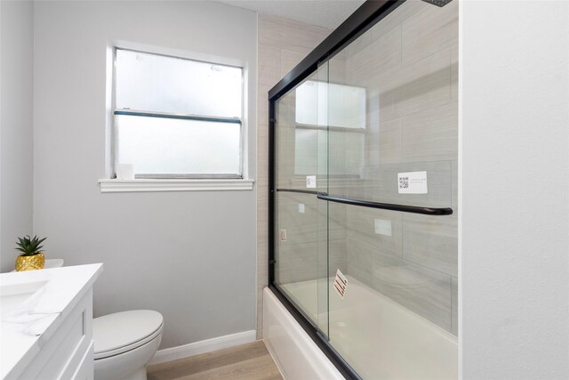 full bath featuring shower / bath combination with glass door, vanity, toilet, baseboards, and wood finished floors