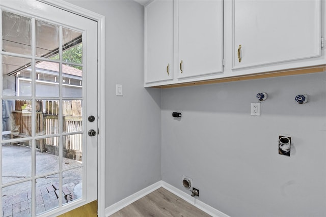 clothes washing area featuring hookup for an electric dryer, hookup for a gas dryer, cabinet space, wood finished floors, and baseboards