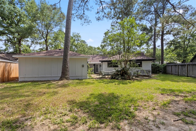 rear view of house featuring a fenced backyard, board and batten siding, and a yard