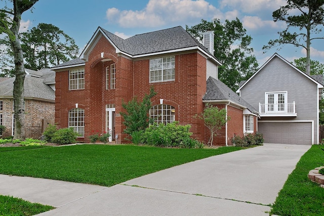 colonial home with brick siding, a garage, a front yard, a chimney, and concrete driveway