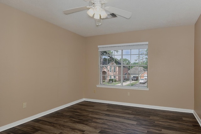 spare room with baseboards, a ceiling fan, dark wood finished floors, and visible vents