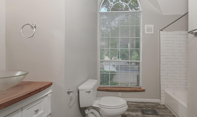 bathroom with visible vents, wood finished floors, toilet, baseboards, and bathtub / shower combination