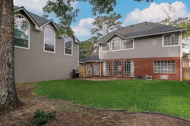 rear view of property featuring brick siding, fence, a yard, and a chimney