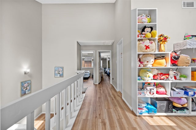 hall with visible vents, attic access, baseboards, and wood finished floors