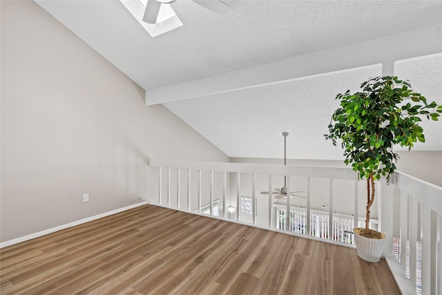 bonus room featuring baseboards, a ceiling fan, lofted ceiling with skylight, and wood finished floors