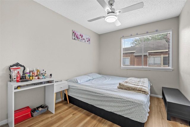 bedroom featuring a ceiling fan, a textured ceiling, baseboards, and light wood-type flooring