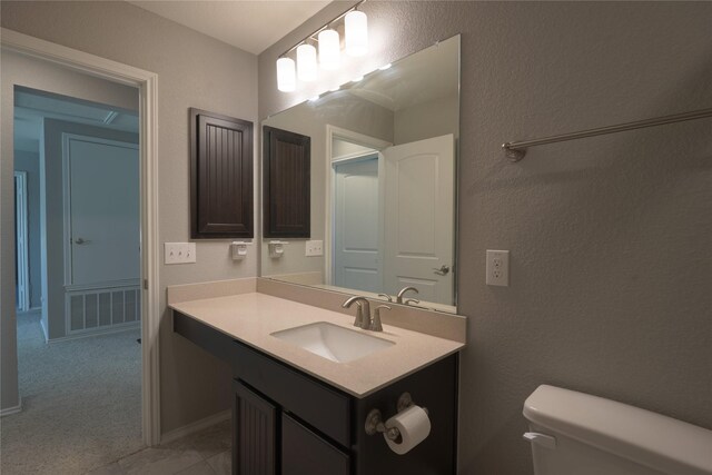 bathroom featuring visible vents, a textured wall, toilet, and vanity