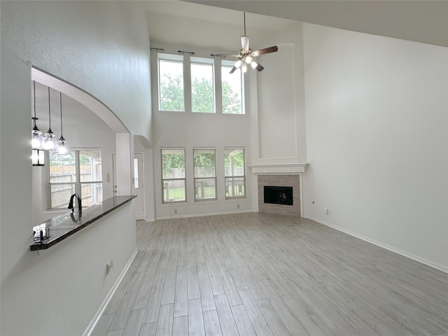 5310 Flagridge Ln, Houston, TX 77066 - unfurnished living room with a high ceiling, a ceiling fan, light wood-style floors, a fireplace, and baseboards